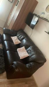 a leather couch in a living room with two pillows at M&M Apartman in Tiszafüred