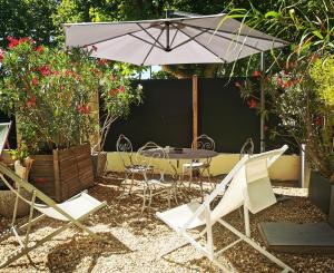 a patio with a table and chairs and an umbrella at Studios MISTRAL21 en Camargue in Salin-de-Giraud