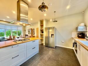 a large kitchen with white cabinets and a stainless steel refrigerator at Penmorfa -4 Bed-3 Bath-Coastal Retreat Sleeps 9 in Trearddur