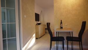 a dining room with a table with chairs and a bottle of wine at Jelena Lapčići Budva in Budva