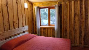 a bedroom with a pink bed and a window at Refugio entre Coihues in Melipeuco