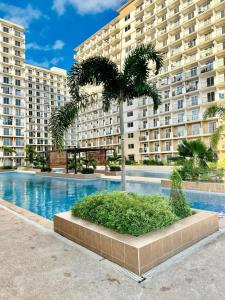 a palm tree in front of a large building at Cloud Nine Poolview Condo Near Mactan Airport in Suba