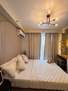 a bedroom with a large white bed and a window at Cloud Nine Poolview Condo Near Mactan Airport in Suba +48 photos