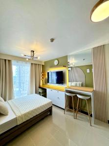 a bedroom with a bed and a desk and a television at Cloud Nine Poolview Condo Near Mactan Airport in Suba