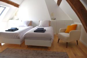 twee bedden en een stoel in een zolderkamer bij Charmante maison avec jardin et air conditionné au coeur d'un village historique ! in Verneuil-en-Bourbonnais
