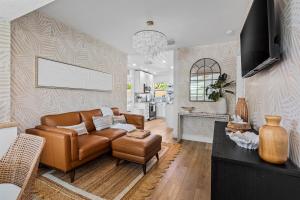 a living room with a brown leather couch and a kitchen at Walk to Atlantic Ave Pool Recently Renovated in Delray Beach