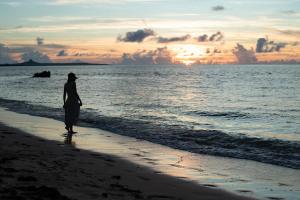 a woman standing on the beach watching the sunset at 陽月-Hizuki- in Nakijin