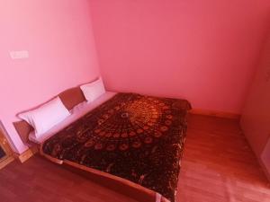 a bedroom with a bed in a pink room at Tashi Khangsar in Padam +2 photos