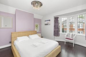 a bedroom with a large white bed and a chandelier at Pebble Corner with Free Parking By My Getaways in Worthing +15 photos