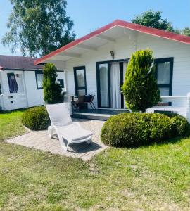 a white chair on a patio in front of a house at Domki Marina Rowy in Rowy