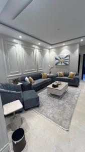 a living room with blue couches and a coffee table at شقة مميزه بتصميم عصري in Baljurashi