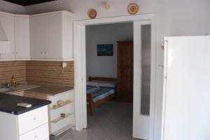 a kitchen with white cabinets and a bed in a room at Sunray Studios Asprovalta in Asprovalta