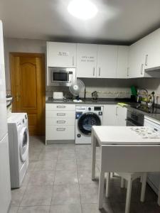 a kitchen with white cabinets and a washer and dryer at Plaza Guest House in Madrid