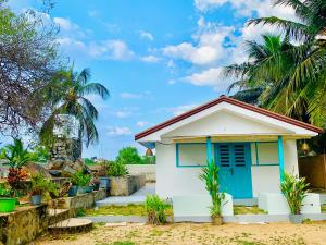 a small house with a blue door and palm trees at Sun Rock Villa Arugambay in Arugam Bay