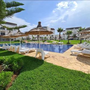 Cabonegro appartement في كابو نيغرو: وجود مسبح في المنتجع مع كراسي الصالة والمظلات