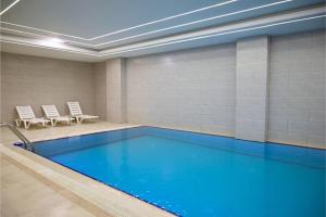 a swimming pool with chairs in a room with a pool at Coral Hotel in Duhok