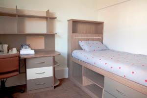 a small bedroom with a bunk bed and a desk at Keynes College in Canterbury