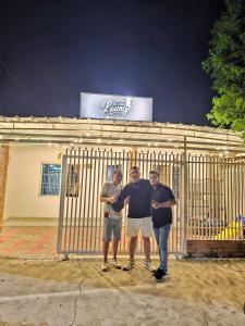 a group of three men standing in front of a gate at La Tribuna Lounge in Valledupar