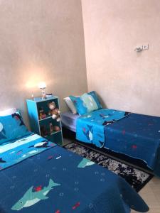 une chambre avec deux lits et un couvre-lit bleu à motif requin dans l'établissement L'Oasis del Maria Fatima, à Agadir nʼ Aït Sa