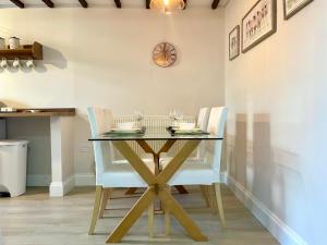 einen Esstisch mit zwei weißen Stühlen und einem Glastisch in der Unterkunft Miners cottage(1840)Nr. Brecon,Tower Zip & Bike Pk in Aberdare + 18 Fotos