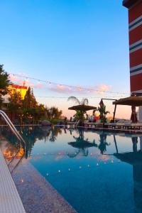 una grande piscina con un tramonto sullo sfondo di Olivia's Hill Resort a Durrës