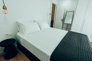 a bedroom with a white bed with a stool and a mirror at Dreamy Glyfada Apartment in Athens
