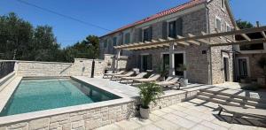 a house with a swimming pool and chairs and a building at Heritage Villa Francheza-Elegant Stone villa near the Beach, Pašman Island , Ugrinić in Ugrinići