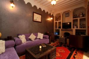 ein Wohnzimmer mit einem lila Sofa und einem Kamin in der Unterkunft Riad Khalid Zrika Marrakech in Marrakesch
