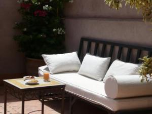eine Bank mit Kissen und ein Tisch mit einem Getränk darauf in der Unterkunft Riad Khalid Zrika Marrakech in Marrakesch