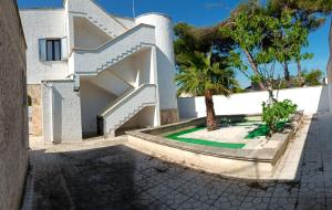 a white house with a staircase and a palm tree at La casa delle isole in Torre Chianca