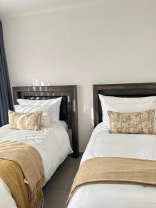 two beds sitting next to each other in a bedroom at Elyon Suites in Kempton Park