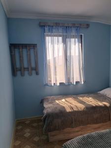- une chambre avec un mur bleu et une fenêtre dans l'établissement Elmira B&B, à Tatev
