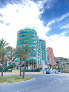 ビリャホヨサにあるParaiso Costero en Benidormの通りの前にヤシの木が茂る高い建物