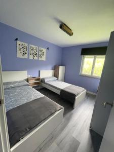 two beds in a room with purple walls at La Caleya de Ozanes 