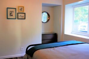 a bedroom with a bed and a mirror and a window at Elegant Carmel Cottage in Carmel