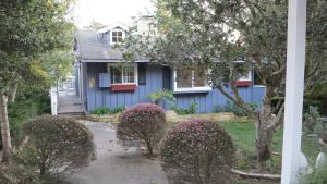 a blue house with bushes in front of it at Elegant Carmel Cottage in Carmel +4 photos
