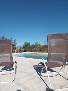 2 sillas de jardín sentadas junto a una piscina en Bello atardecer Uribe, en Uribelarrea