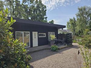 a black tiny house with a porch at 4 person holiday home in FARHULT-By Traum in Farhult