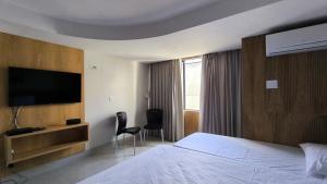 a hotel room with a bed and a flat screen tv at Apartamento a beira mar in Natal