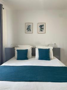 ein Bett mit blauen und weißen Kissen darauf in der Unterkunft Nid douillet a la campagne in Saint-Jean-de-Bournay