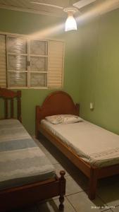 two beds in a room with green walls at RECANTO DA IZAURINHA in Olímpia