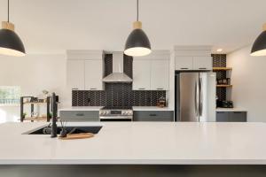 a kitchen with white cabinets and a refrigerator at Chalet Origine St-Come - SPA in Saint Come