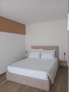 a bedroom with a large bed with white sheets at Casinhas do Campo by Gerês Valley in Campo do Gerês
