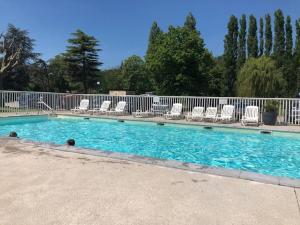 a swimming pool with chaises and chairs in it at L'échappée verte au bord de l'Eure in Ivry-la-Bataille