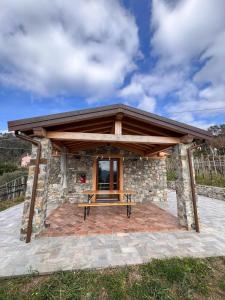 a pavilion with a picnic table in front of a stone building at La Madonnina-house in the Bolano vineyard in Bolano