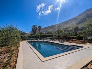 a swimming pool with chairs and mountains in the background at Villa Betta Cuntrariusa con piscina privata e jacuzzi a Scopello in Castellammare del Golfo