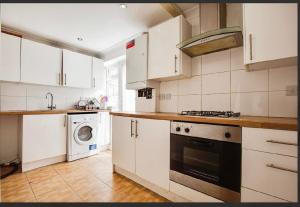South Ruislip StationにあるSpacious 3-Bed Home in Northolt Perfect for Contractors Sleeps 6のキッチン(白いキャビネット、洗濯機、乾燥機付)