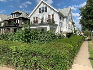 a white house with a hedge in front of it at The Paradise House steps from the Heart of Hertel in Buffalo