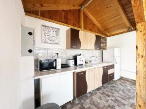 a kitchen with white appliances and wooden ceilings at Relax by the Sea Rooms next to Nibiru in Costinesti
