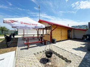 a picnic table with an umbrella next to a building at Relax by the Sea Rooms next to Nibiru in Costinesti